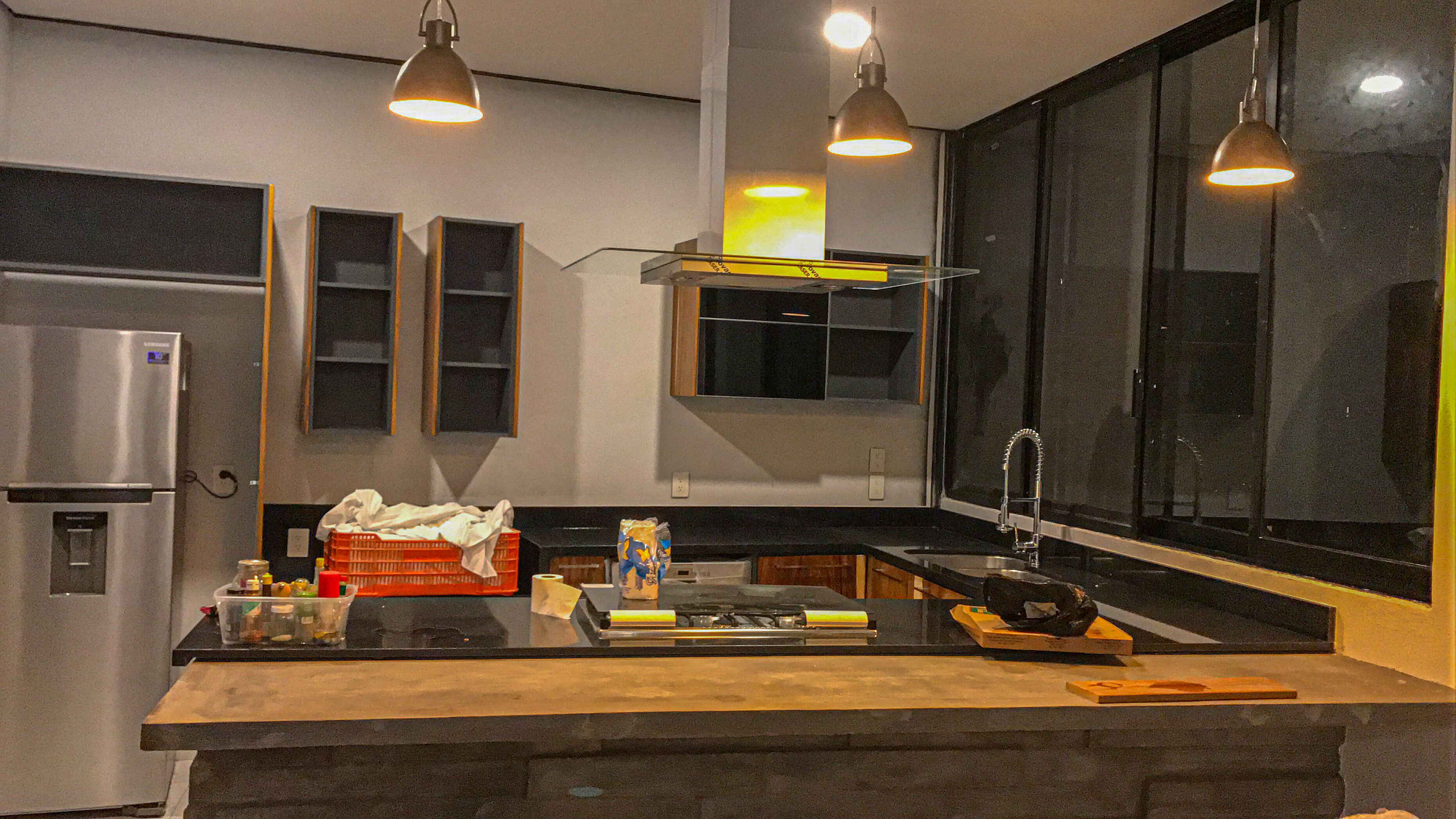 Cocina abierta de Casa MG con isla de concreto pulido e iluminación de diseño, construcción residencial Fer Et Ciment León